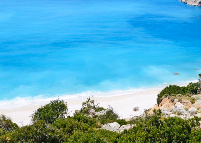 Spiaggia bianca e mare cristallino nel Mediterraneo Orientale, vista ideale per una crociera estiva.
